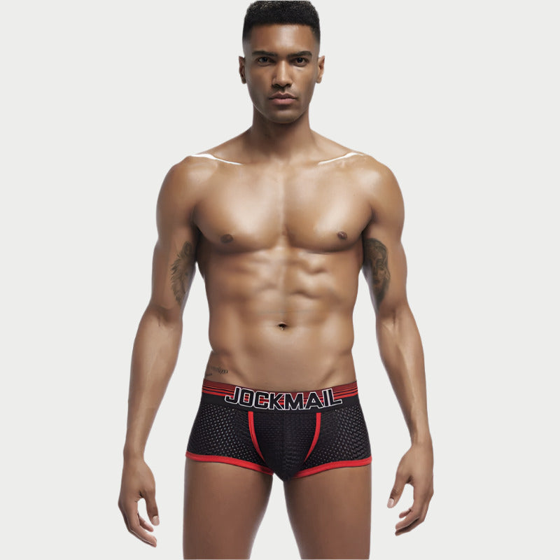 This image features a model wearing Jockmail Performance Mesh Quick-Dry Boxer Briefs. The boxer briefs are designed with a sleek, black mesh fabric and accented with red trim.