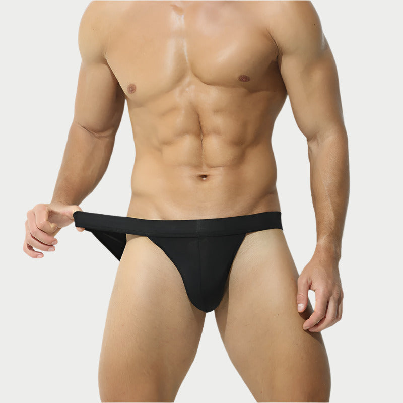 A model wearing a black jockstrap brief, showcasing the fit and design of the product.