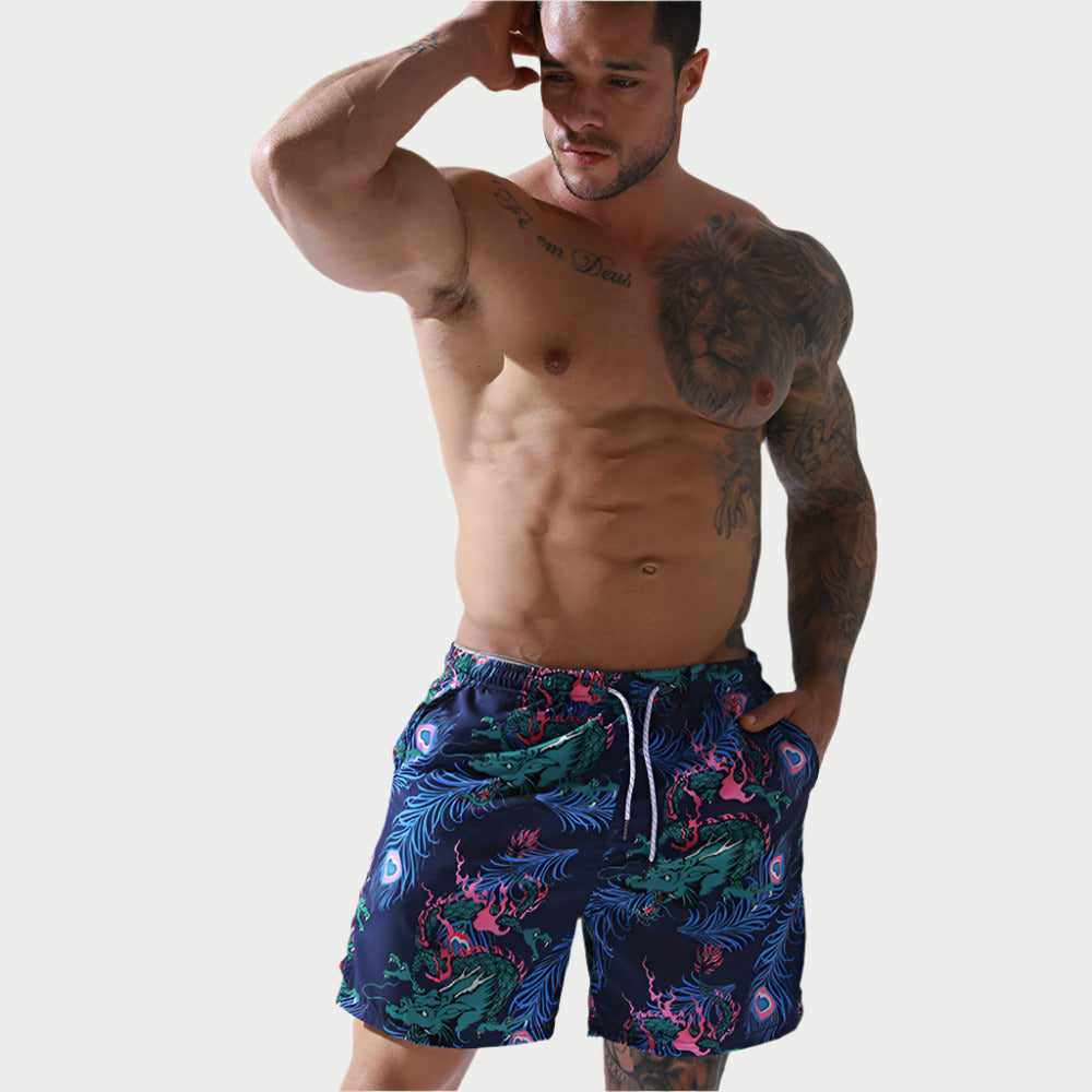 A man wearing peacock print swim shorts with a waistband.