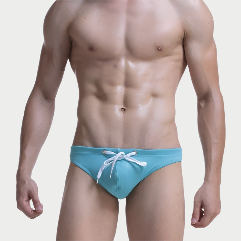 This image displays a pair of men's swim briefs, presented in a striking shade of teal. The swim briefs are designed with a minimalist aesthetic, featuring a drawstring waistband accented with a white tie, which adds a touch of elegance.