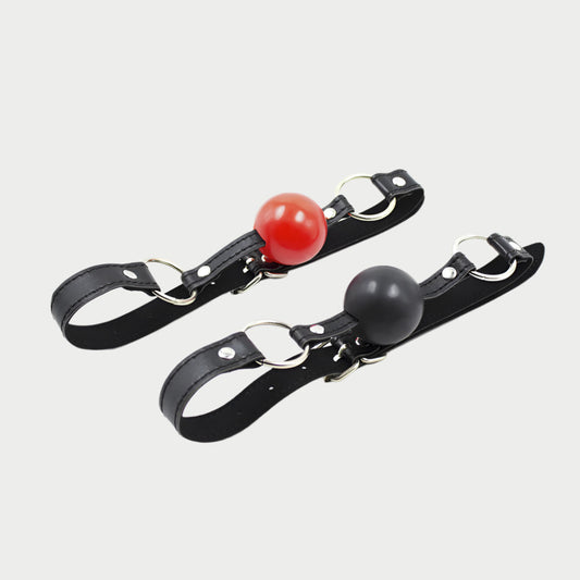 Two black faux leather ball gags with red and black balls, featuring adjustable straps.