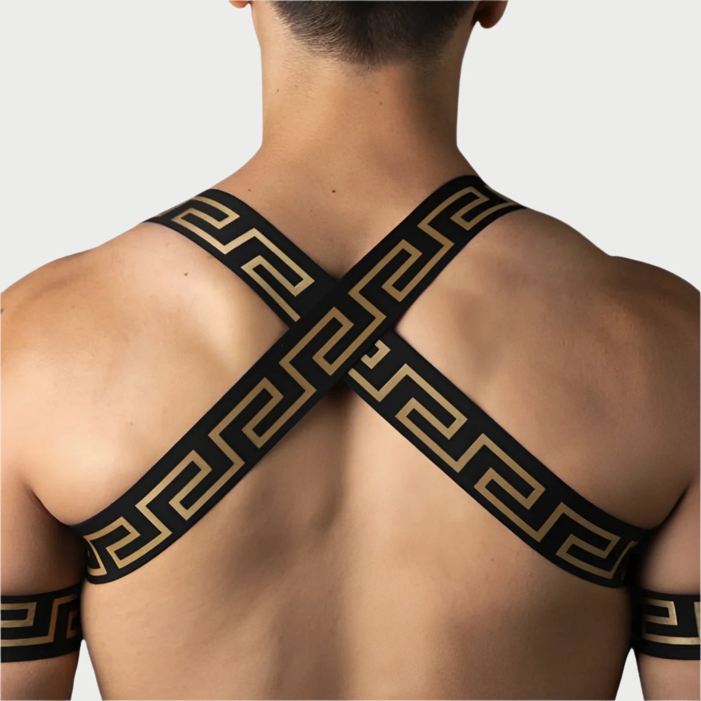 Person wearing a black and gold patterned shoulder strap against a light blue background