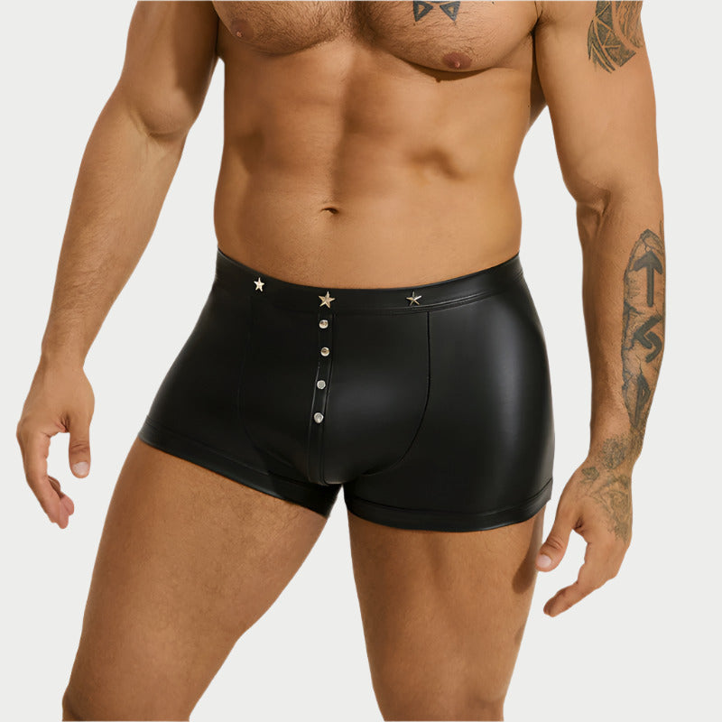Man wearing black leather-style boxer briefs on a white background