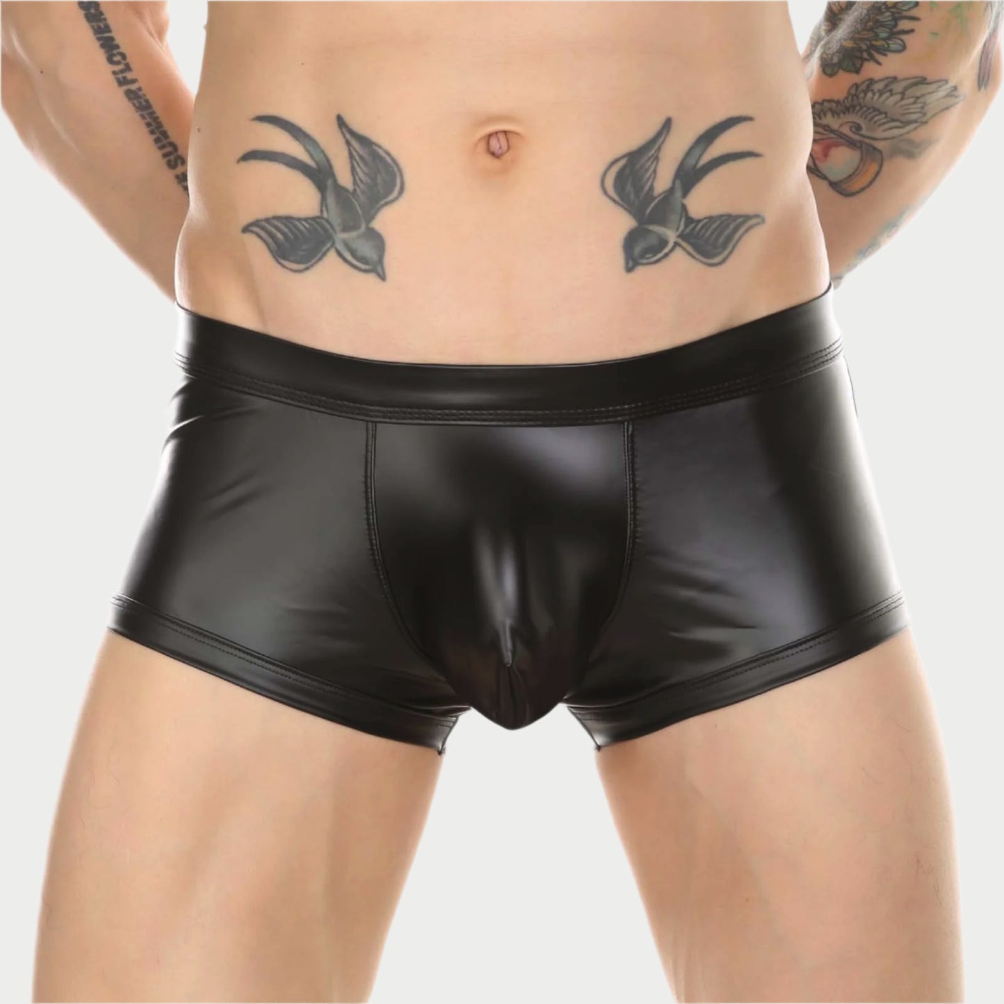 This image features a pair of sleek, black faux leather boxer briefs, designed with a provocative open-back style. The briefs are modeled by a male, highlighting the snug fit and the shiny, smooth texture of the material.