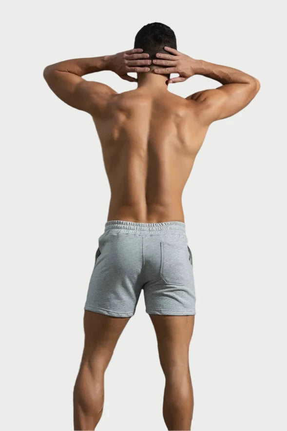 Man wearing gray shorts from behind on a gray background
