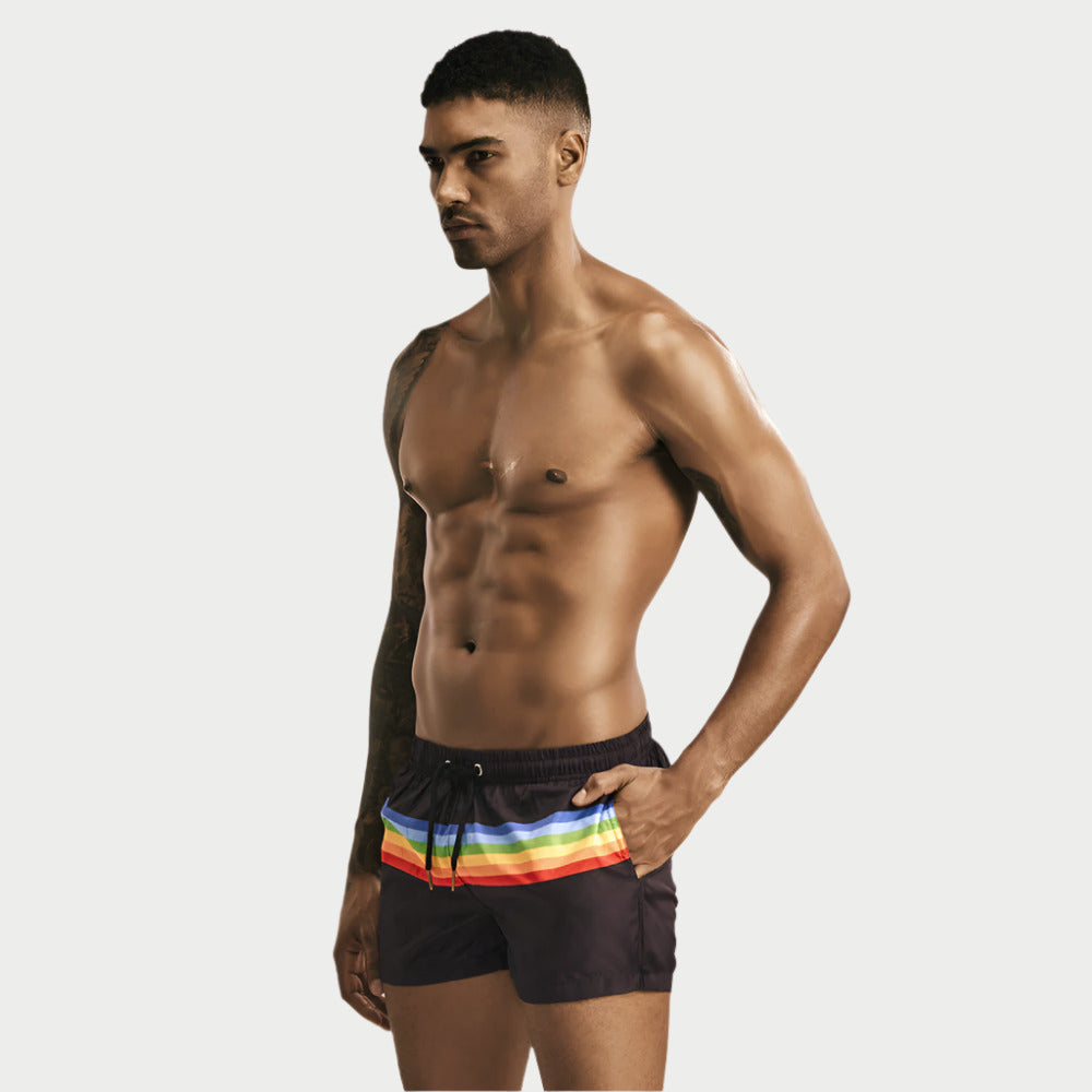 A man wearing striped casual swim shorts with a multicolor design.