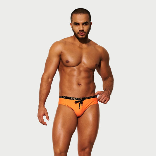 Man wearing orange swim briefs on a white background