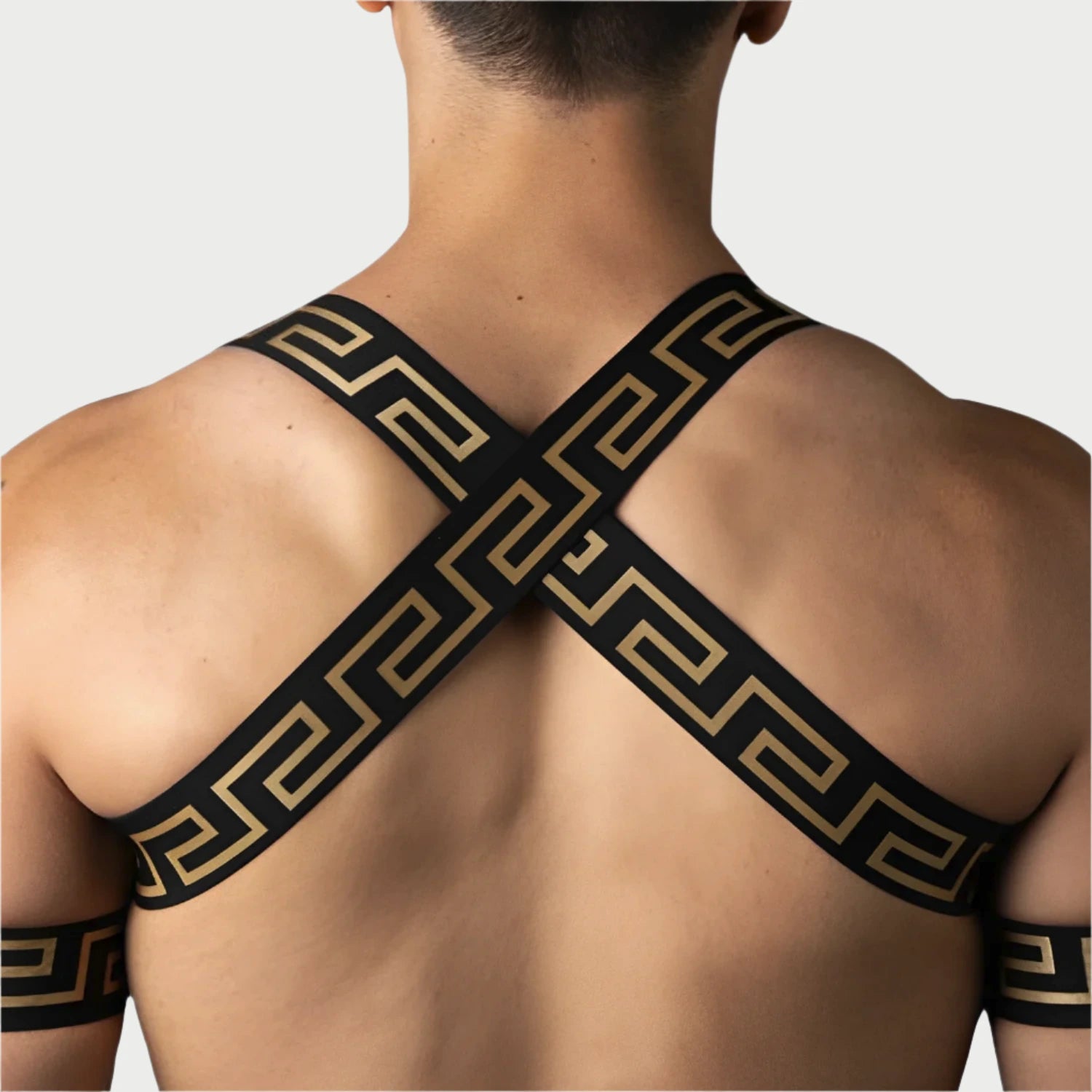 Person wearing a black and gold patterned shoulder strap against a light blue background
